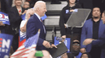 Man In Suit Standing Before Crowd With Signs GIF