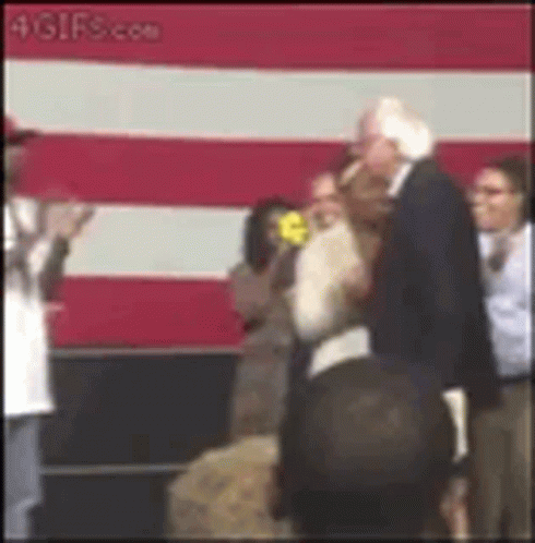 Man In Suit Standing Before Flag GIF