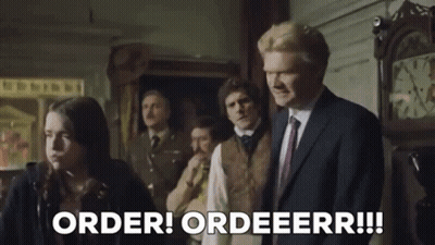 Man In Suit Standing Before Group And Clock GIF