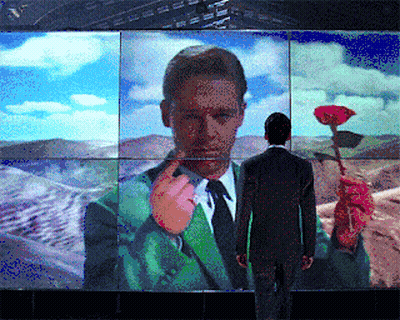 Man In Suit Standing Before Self-Portrait GIF