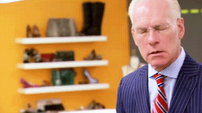 Man In Suit Standing Before Shoe Shelf GIF