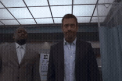 Man In Suit Standing Before Sign GIF