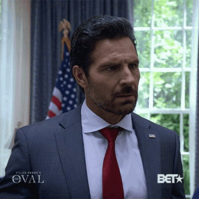 Man In Suit Standing Before Window With Beta GIF
