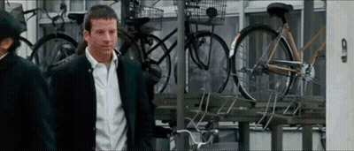 Man In Suit Standing In Front Of Bicycles GIF