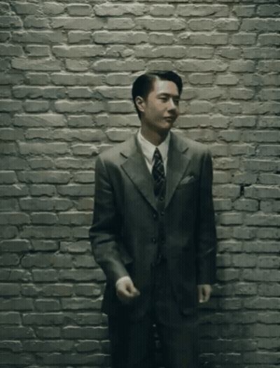 Man In Suit Standing In Front Of Brick Wall GIF