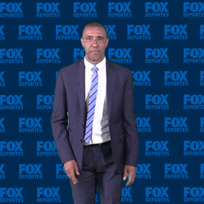Man In Suit Standing In Front Of Fox Deportes Wall GIF