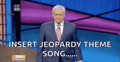 Man In Suit Standing In Front Of Jeopardy Screen GIF