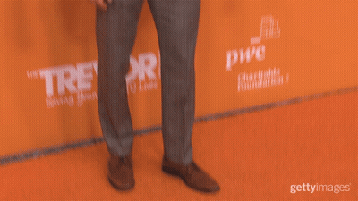 Man In Suit Standing In Front Of Revor Sign GIF