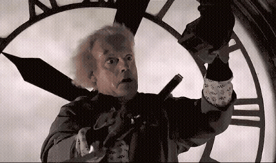 Man In Suit Standing In Front Of Roman Numeral Clock GIF