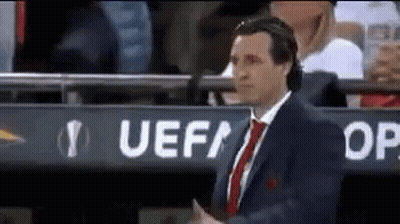 Man In Suit Standing In Front Of UEFA Sign GIF