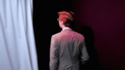 Man In Suit Standing In Front Of White Curtain GIF