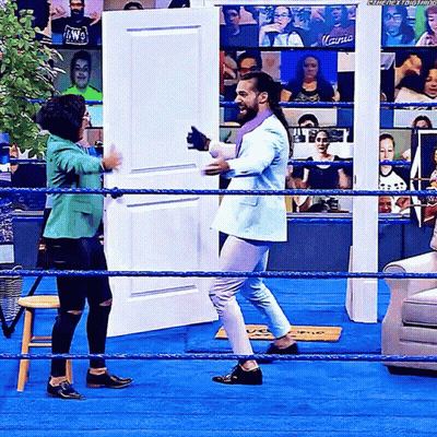 Man In Suit Standing In Wrestling Ring With Woman In Green Jacket GIF
