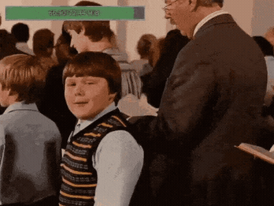 Man In Suit Standing Next To Boy In Striped Vest In Crowd GIF