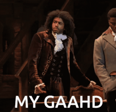 Man In Suit Standing Next To Chair Saying My Gaahd GIF