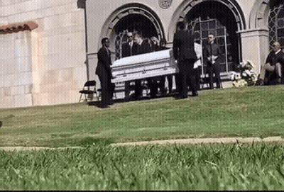 Man In Suit Standing Next To Coffin GIF