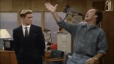 Man In Suit Standing Next To Seated Man In Office GIF