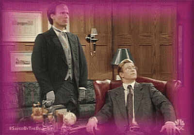 Man In Suit Standing Next To Seated Man GIF