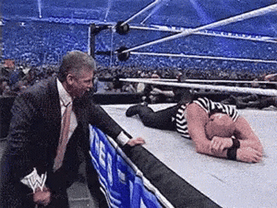 Man In Suit Standing Next To Wrestler On Floor GIF