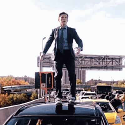 Man In Suit Standing On Car On Highway GIF