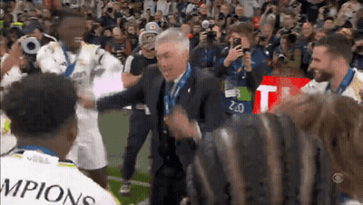 Man In Suit Surrounded By Soccer Champions GIF