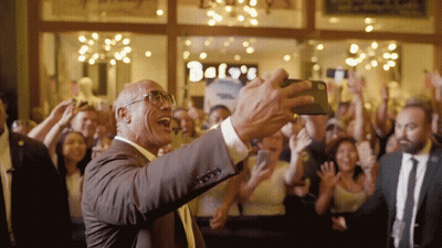 Man In Suit Taking Selfie In Front Of Bels Store GIF