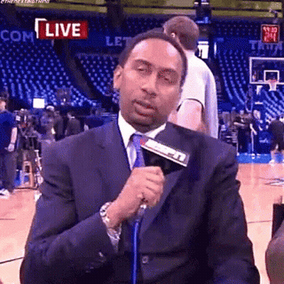 Man In Suit Talking Into Microphone On Basketball Court GIF