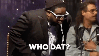 Man In Suit Talking Into Microphone While Another Says Who Dat GIF