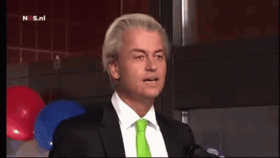 Man In Suit Talking Into Microphone With Green Tie GIF