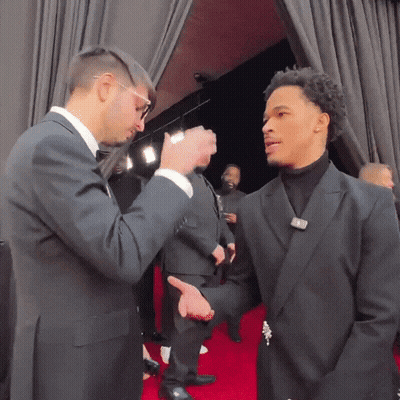 Man In Suit Talking To Another In Black Suit On Red Carpet GIF