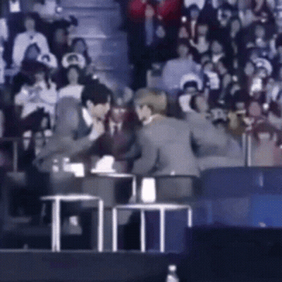 Man In Suit Talking To Another In Crowd GIF