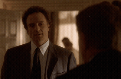 Man In Suit Talking To Another In Dark Room GIF