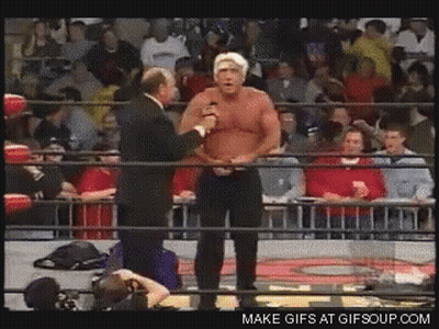 Man In Suit Talking To Another In Wrestling Ring With Crowd GIF