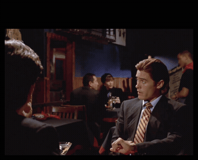 Man In Suit Talking To Another Man With Gotten Us In Behind Him GIF