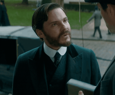 Man In Suit Talking To Man In Hat GIF