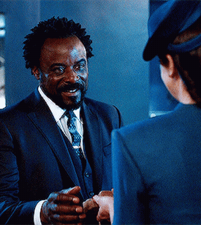 Man In Suit Talking To Woman In Blue Hat GIF