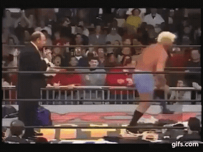 Man In Suit Talking To Wrestler In Blue Shorts GIF