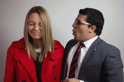 Man In Suit Talks To Woman In Red Trench Coat GIF
