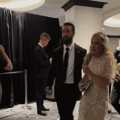 Man In Suit Walking Beside Woman In White Dress GIF