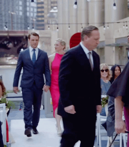 Man In Suit Walking Down Aisle Holding Hands With Woman In Pink Dress GIF