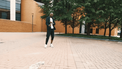 Man In Suit Walking Down Brick Street GIF