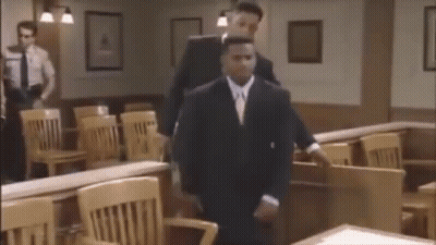 Man In Suit Walking In Courtroom With Man Behind GIF