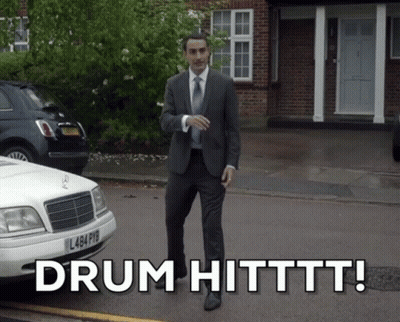 Man In Suit Walking Next To White Car Saying Drum Hitttt GIF