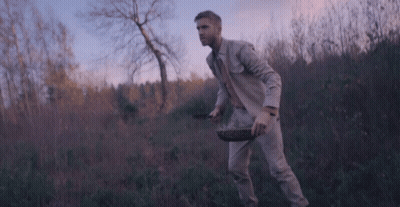 Man In Suit Walking Through Field With Basket GIF