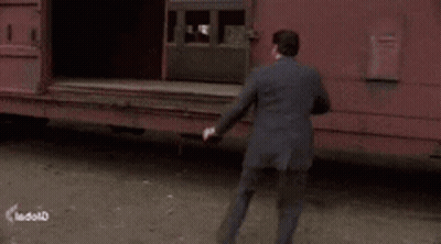 Man In Suit Walking Towards Red Train Car GIF