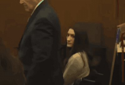 Man In Suit Walks Past Woman In Chair GIF
