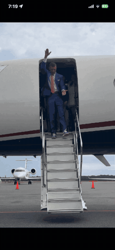 Man in Suit Waving From Plane Stairs