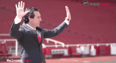 Man In Suit Waving In Front Of Arsenal Stadium GIF