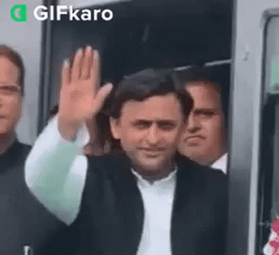 Man In Suit Waving In Front Of Bus GIF