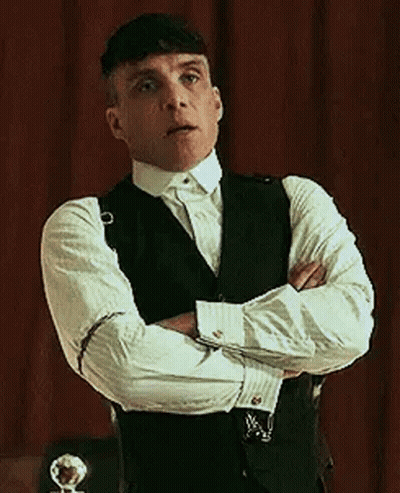 Man In Suit With Arms Crossed In Front Of Red Curtain GIF