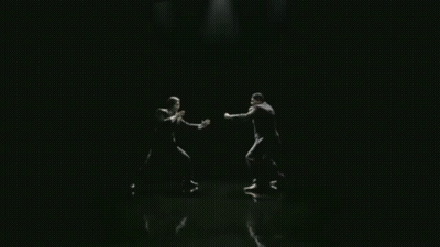 Man In Suit With Arms Outstretched In Dark Room GIF